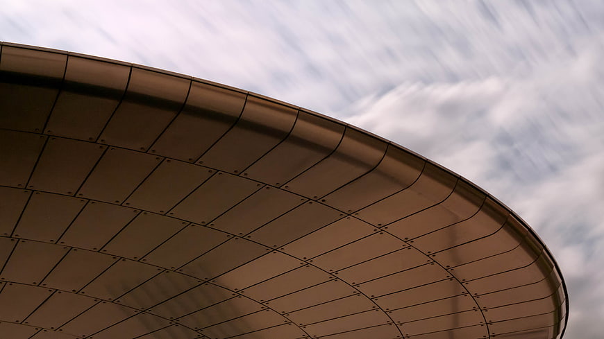 Curved Metal Roof Architecture Against Cloudy Sky
