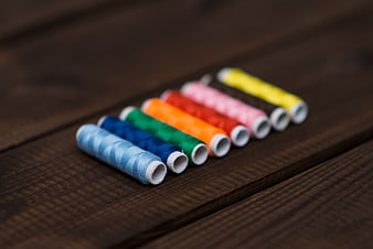 Colorful spools of thread on dark wooden background