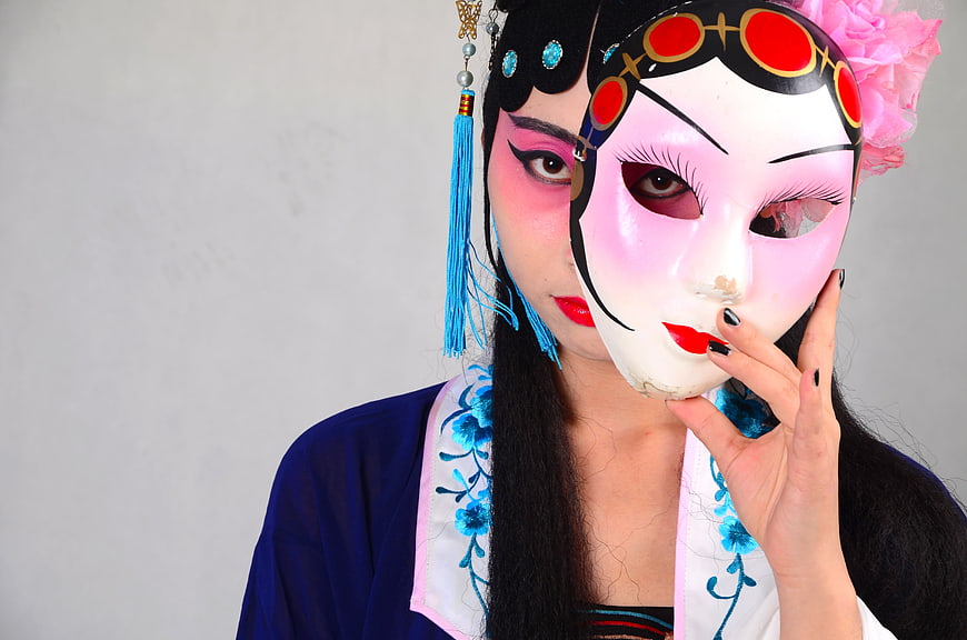 Woman in Peking Opera Costume Holding Traditional Mask