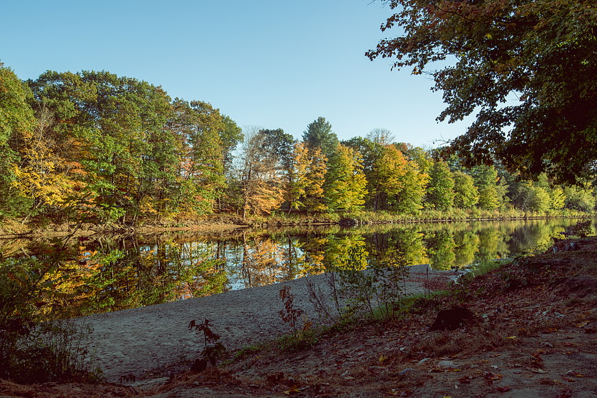 Serene Autumn River Landscape with Vibrant Foliage Reflections