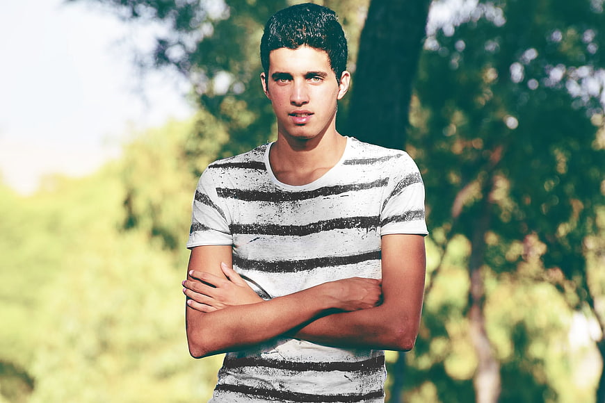 Portrait of young man with crossed arms in park