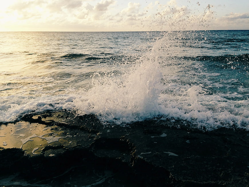 Ocean Wave Splashing on Rocky Shore at Sunset