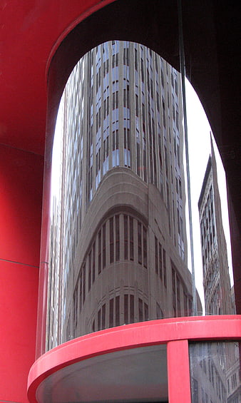 Red architectural frame reflecting distorted city skyscraper