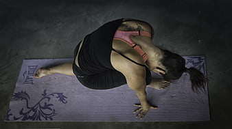 Overhead view of woman practicing yoga pose on purple mat
