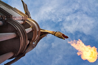Dragon statue breathing fire against blue sky at Universal Studios