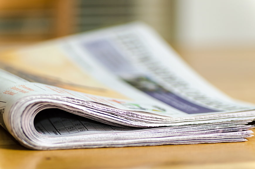 Close-up of folded newspaper on wooden table