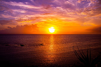 Vibrant Orange Sunset Over The Sea With Purple Clouds