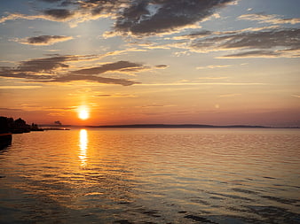 Golden Sunset Over Calm Ocean with Cloud Reflections