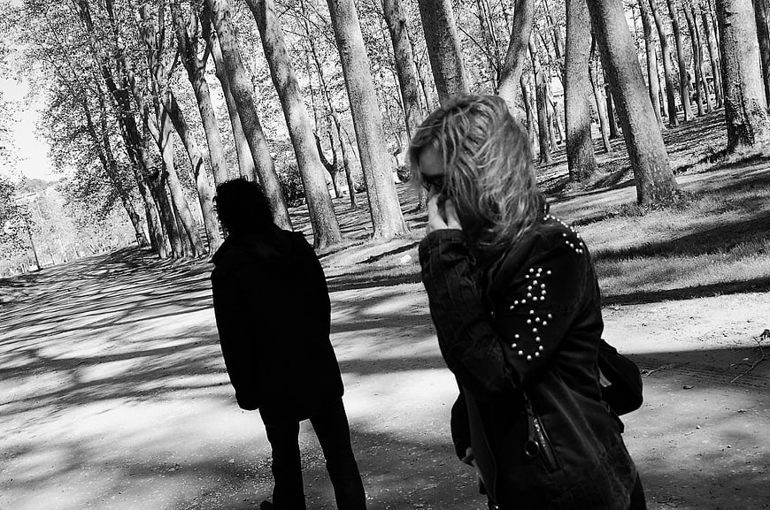 Black and white photo of couple walking apart in forest