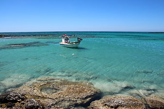 Small boat anchored in clear turquoise tropical waters