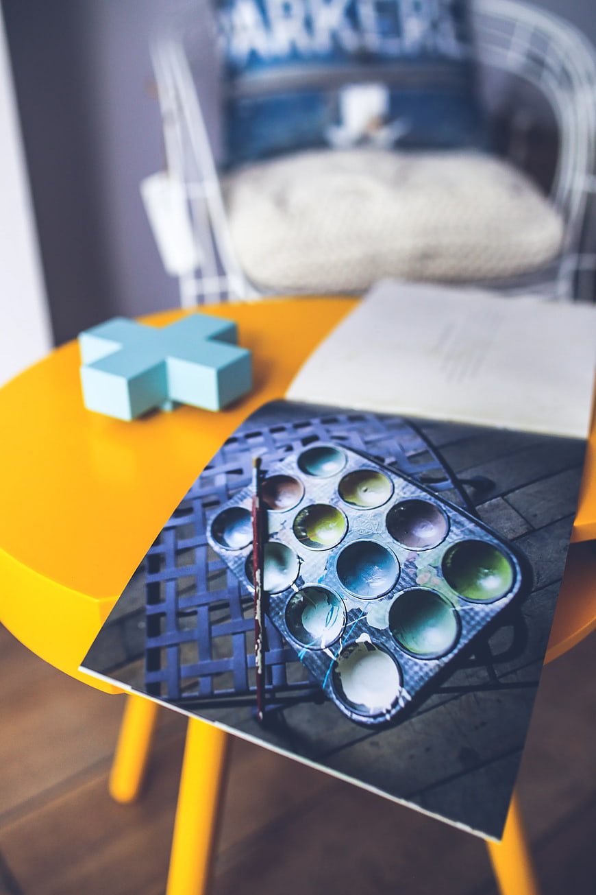 Art supplies on yellow table with paint palette photo