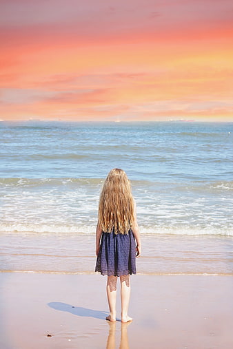 Young girl standing on beach at sunset