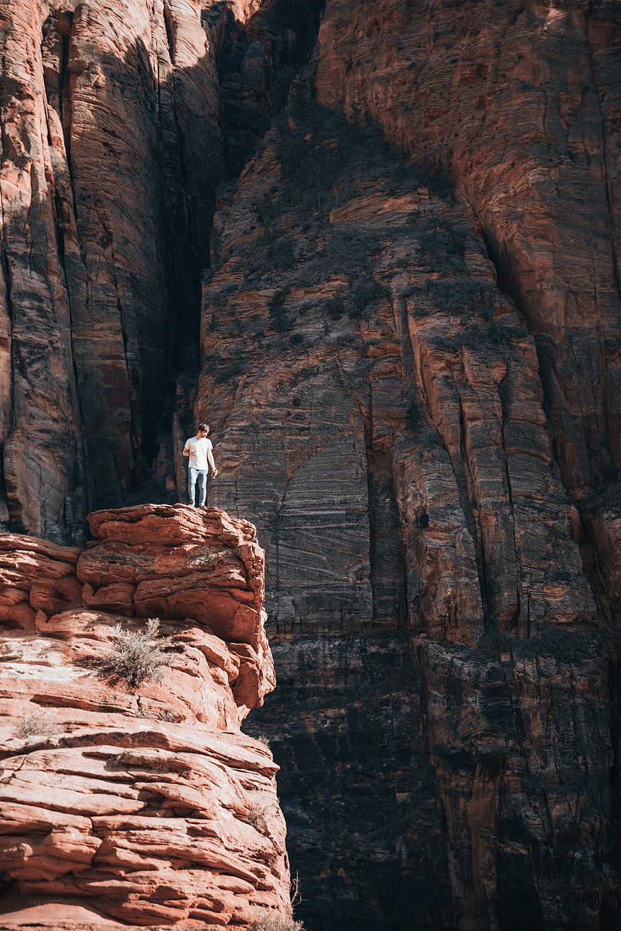 Man Standing on Red Rock Cliff Edge in Canyon