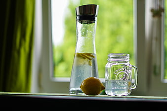 Lemon water in glass carafe and mason jar on windowsill