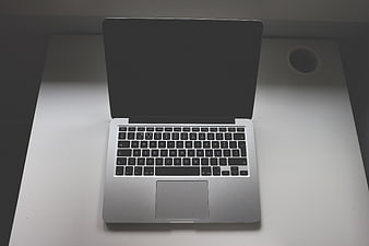 Silver laptop on white desk with cup holder