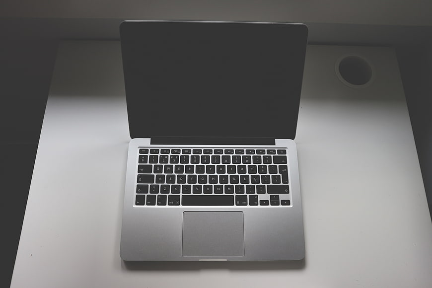 Silver laptop on white desk with cup holder
