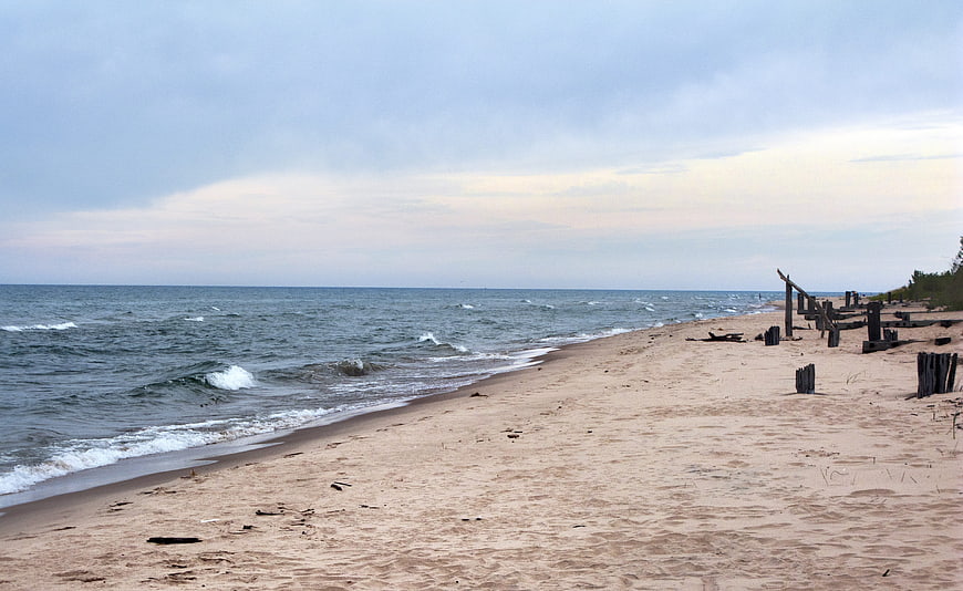 Serene sandy beach with wooden posts and overcast sky
