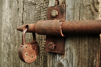 Rusty padlock on weathered wooden door