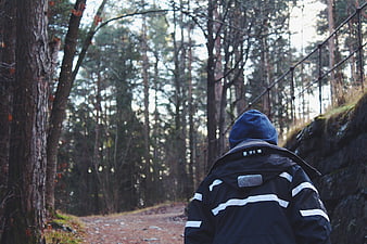 Man hiking on forest trail in blue jacket