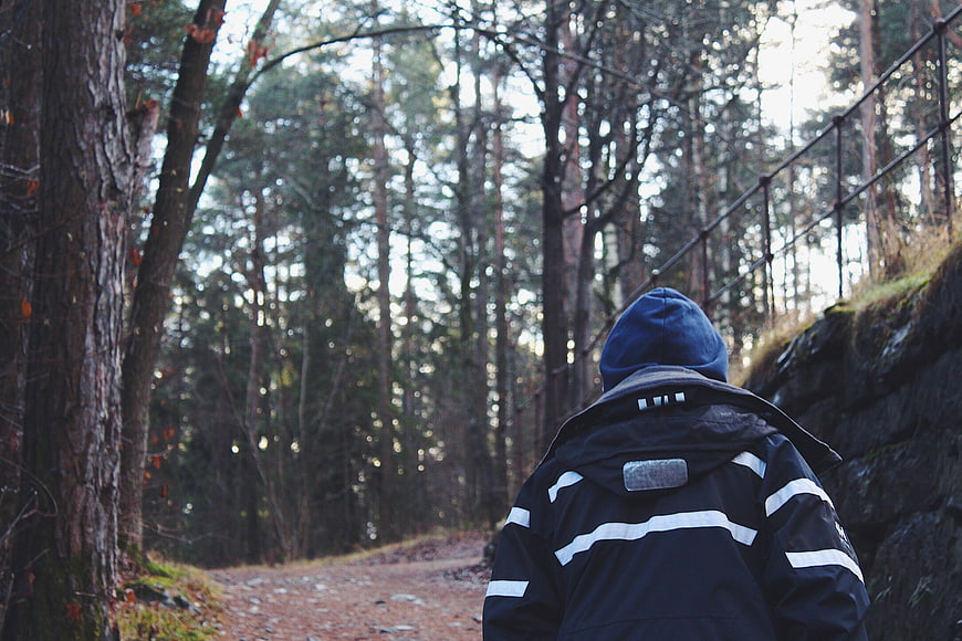 Man hiking on forest trail in blue jacket