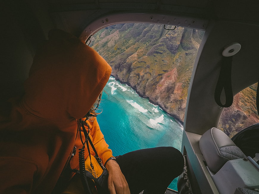 Helicopter passenger viewing coastal cliffs and turquoise ocean