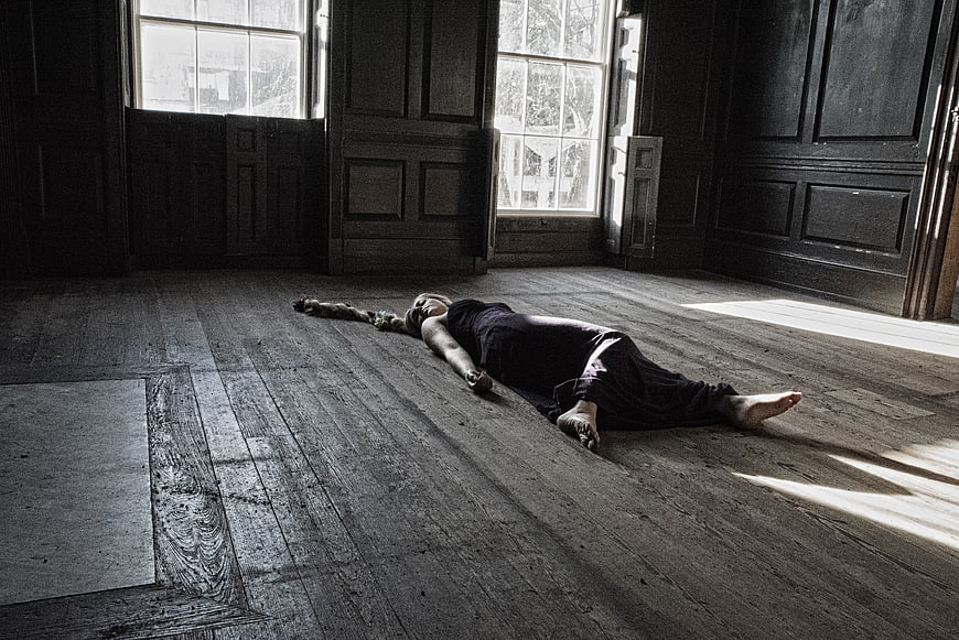 Woman lying on wooden floor in dark room with sunlight
