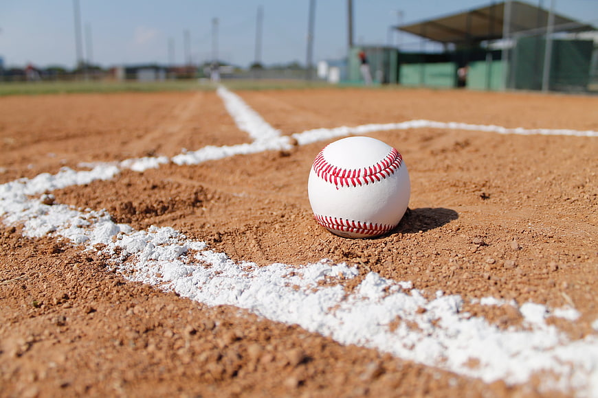 Baseball on dirt field near white chalk line