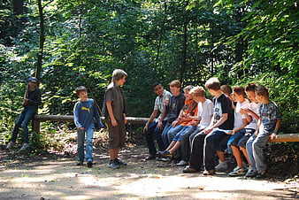 Group of Teenage Boys Sitting on Log in Forest