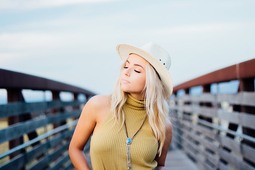 Blonde woman in hat and yellow top on bridge