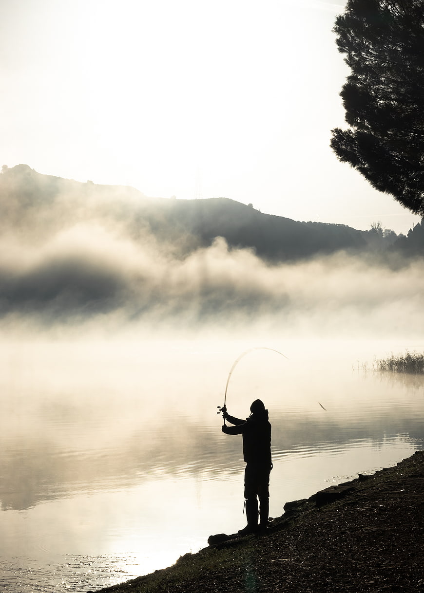 Silhouette of Fly Fisherman Casting in Misty Morning