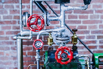 Industrial Pipes and Red Valves on Brick Wall