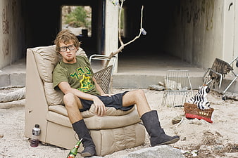 Young man sitting in armchair in abandoned building