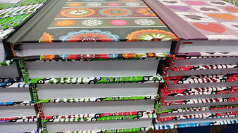 Stack of colorful patterned notebooks with batik and car designs