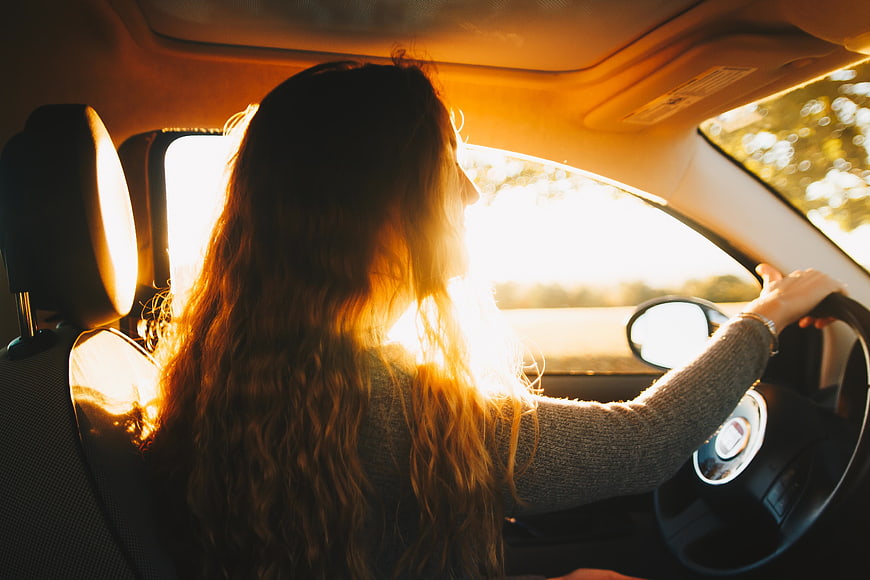 Woman Driving Car in Golden Hour Sunlight