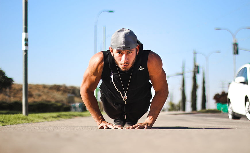 Athletic man in low crouch on asphalt road
