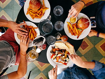 Overhead view of friends eating burgers and fries at a restaurant table
