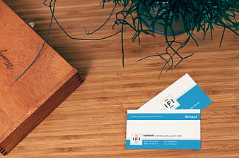 Blue and white business cards on wooden desk with plant