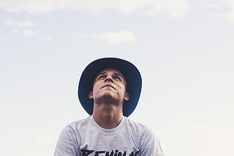 Young man in hat looking up at sky