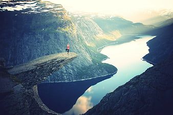 Woman doing yoga on Trolltunga cliff overlooking fjord