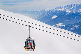 Gondola lift ascending snowy mountain slope with skiers inside