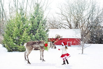 Little Girl in Santa Costume Interacting with Reindeer in Snowy Winter Landscape