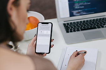 Woman using smartphone app with laptop and notebook