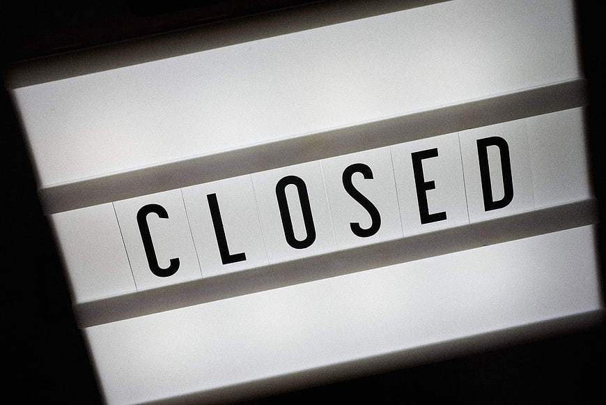 Close-up of a white flip sign displaying the word CLOSED in black letters