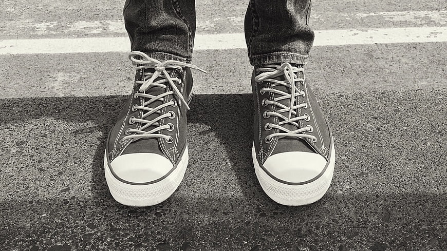 Black and white sneakers on asphalt road