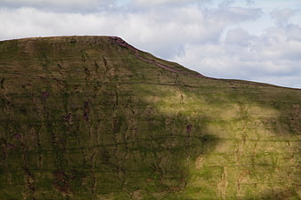 Aerial view of green highland mountain slope with clouds