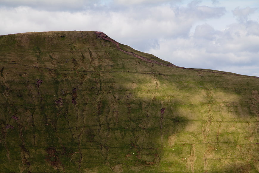 Aerial view of green highland mountain slope with clouds