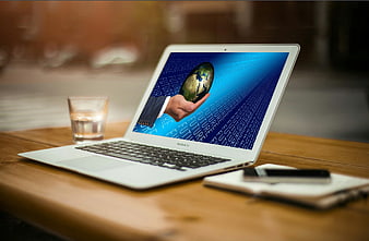 Laptop displaying global business concept with hand holding globe