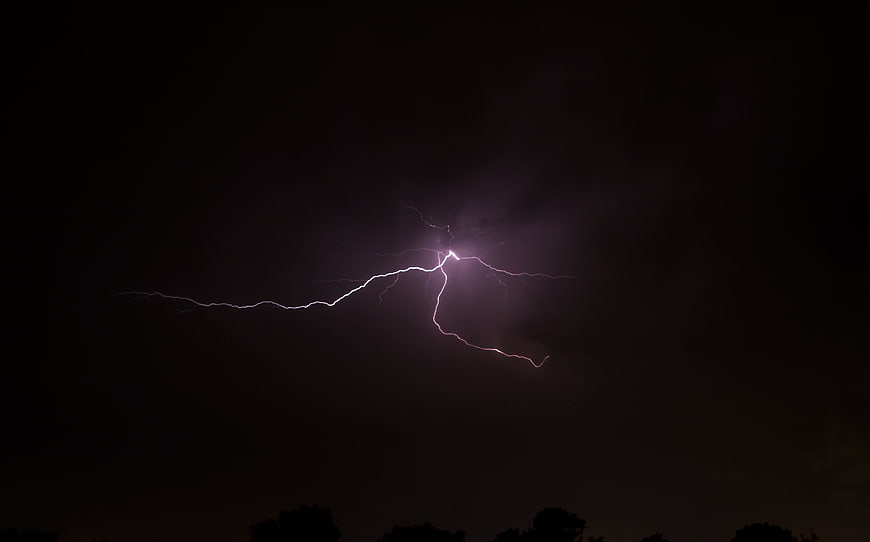 Dramatic lightning bolt striking through dark night sky