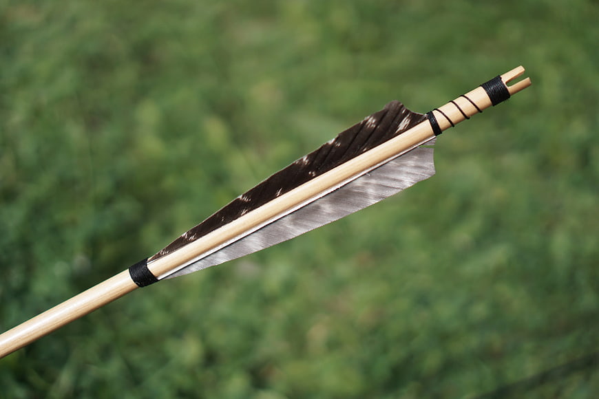 Traditional Wooden Arrow with Feathers on Green Background