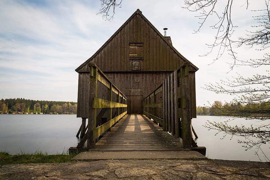 Rustic wooden boathouse on a calm lake with leading lines